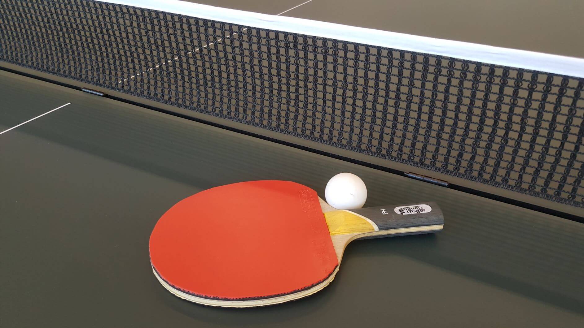 Ein Tischtennisschläger mit Ball auf einer Tischtennisplatte