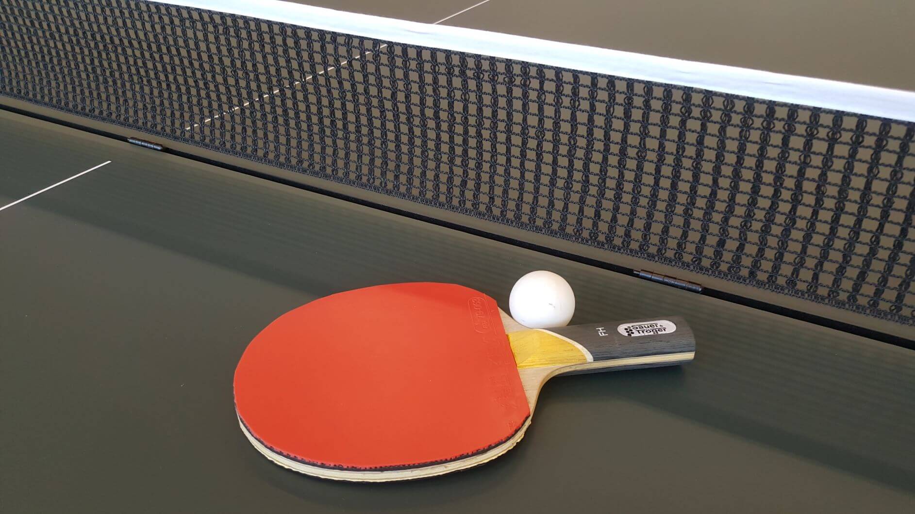 Ein Tischtennisschläger mit Ball auf einer Tischtennisplatte